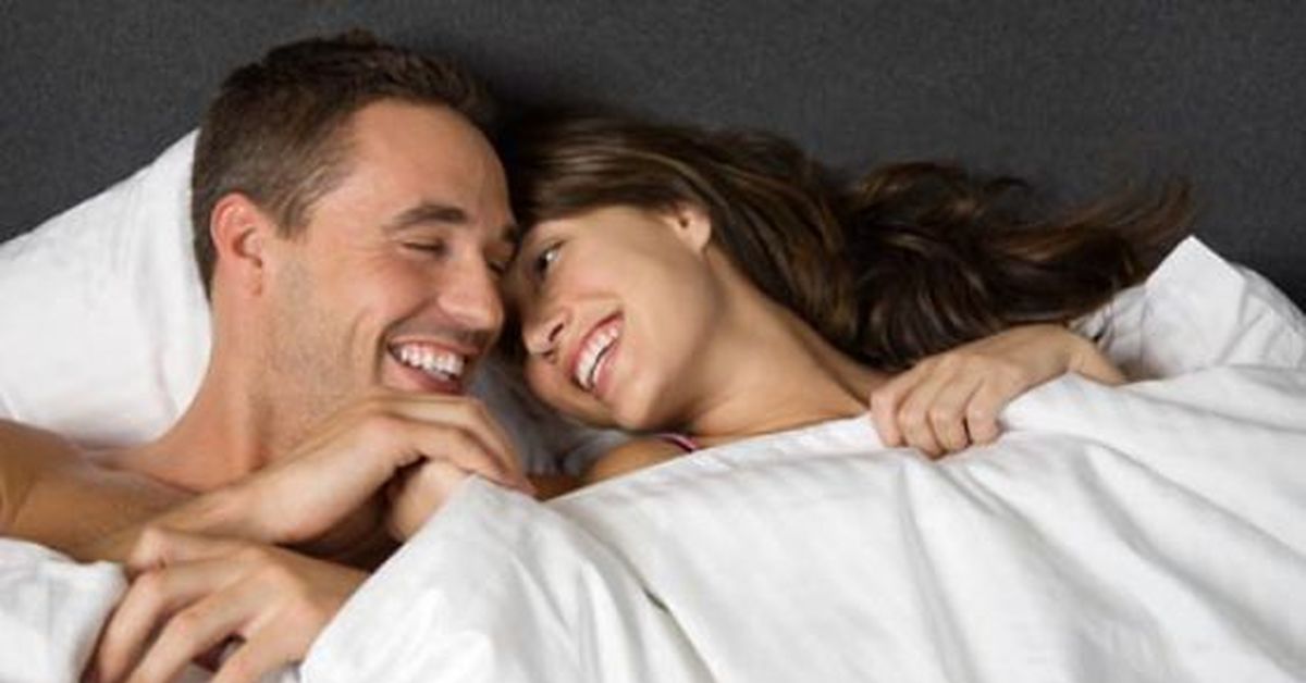 Девушка смеется в постели. Мужчина и женщина смеются в постели. Смеяться на кровати.
