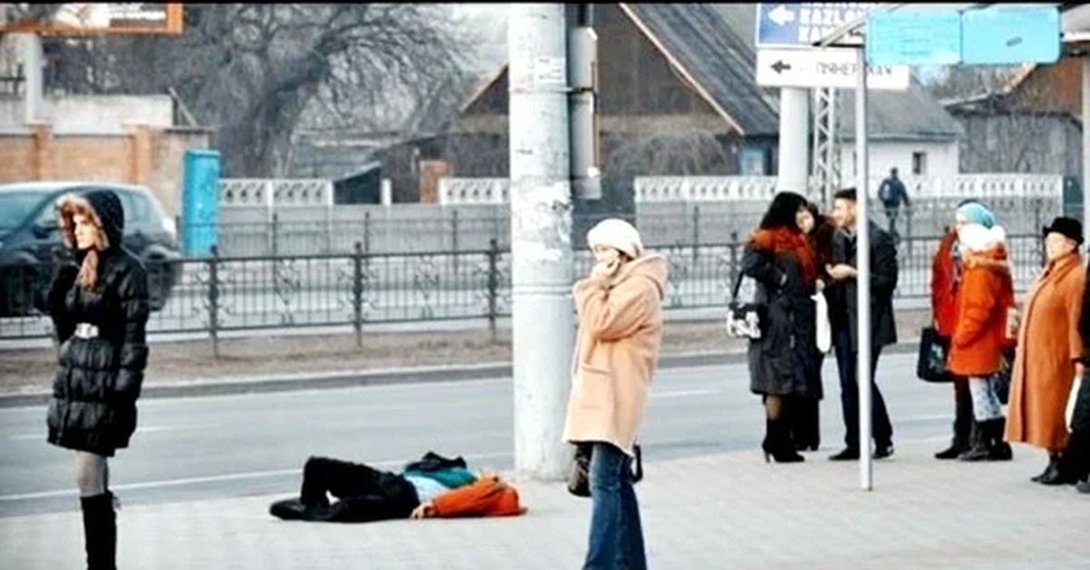 Никто не хочет на улицу. Равнодушие людей на улицах. Человек лежит на остановке.