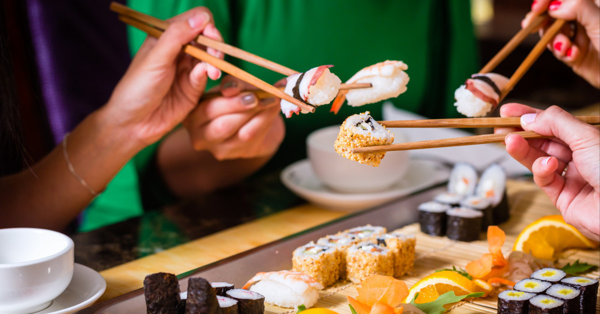 Суши и роллы. Японские палочки для еды. Ест суши. Японская кухня.