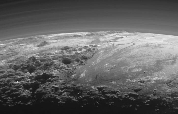 This landscape of majestic mountains and icy plains stretches to the horizon of a small distant world - Pluto. - Milky Way, Universe, Galaxy, Planet, Astronomy, Land, Space, Pluto, Satellites